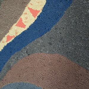Textured rug showing curved bands of grey, blue, and brown, with a cream stripe featuring pink triangle motifs.