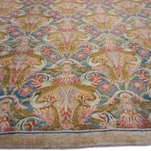 Intricate floral rug design featuring teal, beige, pink, and gold color tones.