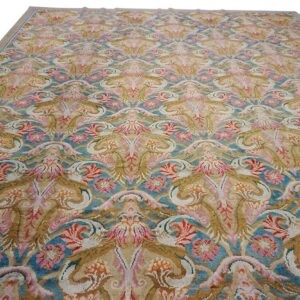 Ornate rug featuring a repeating damask floral motif in beige, teal, pink, gold, and coral colors.