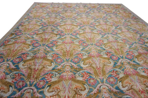 Ornate rug featuring a repeating damask floral motif in beige, teal, pink, gold, and coral colors.