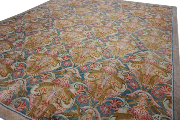 Ornate area rug with teal, rose, tan, and cream foliate motifs and a solid beige border.