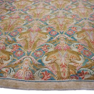 Ornate floral and scroll pattern rug in gold, beige, pink, and bright blue colors.