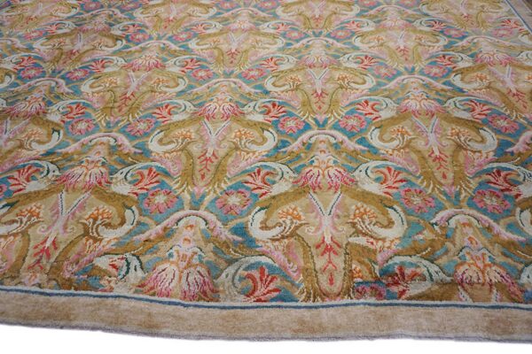 Ornate floral and scroll pattern rug in gold, beige, pink, and bright blue colors.