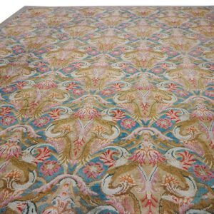 Ornate traditional rug with repeating floral medallions in gold, turquoise, pink, and white.