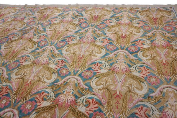 High-pile rug featuring scrolling floral and baroque designs in tan, teal, pink, and cream colors.