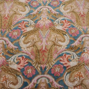 Ornate high-pile rug detail featuring beige, teal, and pink symmetrical floral and scrolling motifs.