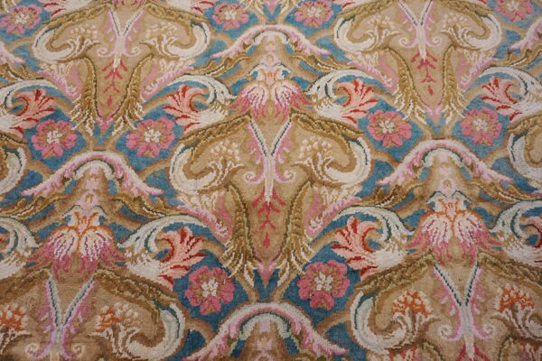 Ornate high-pile rug detail featuring beige, teal, and pink symmetrical floral and scrolling motifs.