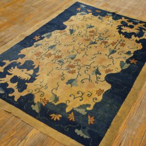 Stylized yellow and indigo patterned rug with rust accents placed on worn wooden flooring.