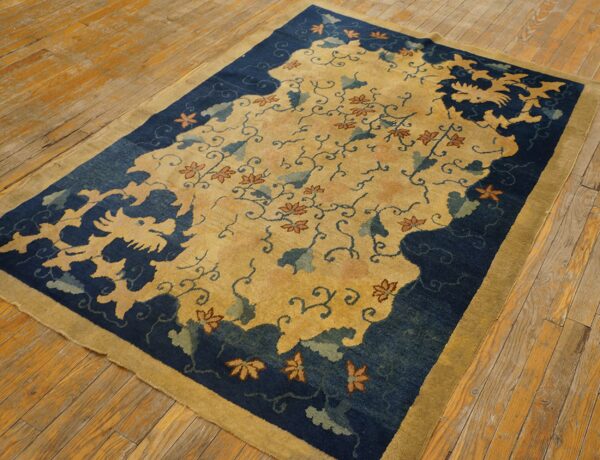 Stylized yellow and indigo patterned rug with rust accents placed on worn wooden flooring.
