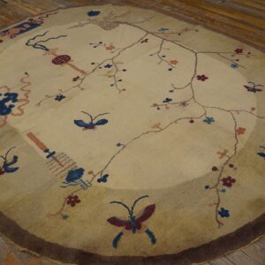 Round low-pile rug featuring a delicate floral and butterfly pattern on a light beige field over wood planks.