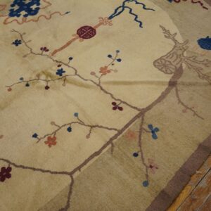 Rounded beige rug features delicate blue and red floral vine designs over rustic wood flooring.