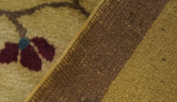 Close-up showing the golden piled side with a burgundy floral design folded over the woven striped backing.