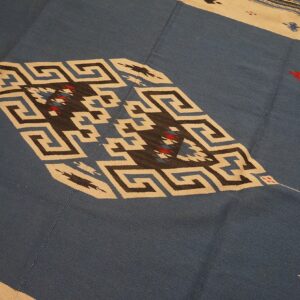 Flat-weave rug with a blue field and a cream border framing geometric Greek key and diamond designs.