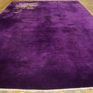 Deep purple, high-pile rug featuring a corner floral motif over light wood plank flooring.