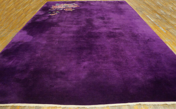 Deep purple, high-pile rug featuring a corner floral motif over light wood plank flooring.