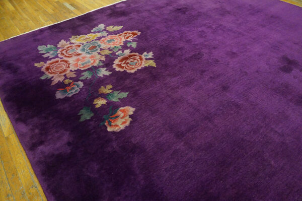 A velvety purple rug with a corner bouquet of pink, peach, and blue flowers rests on hardwood flooring.