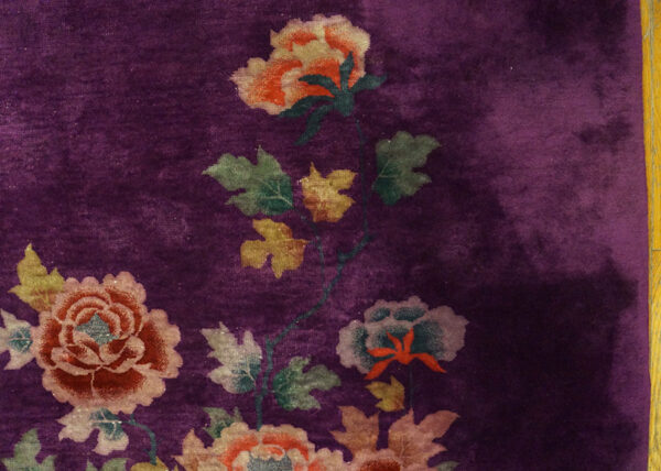 Deep magenta rug detail with glossy pile and large pink, orange, and green floral and leaf motifs.