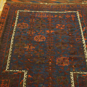 Deep blue and maroon geometric rug featuring medallions and a stepped white inner border on wood flooring.