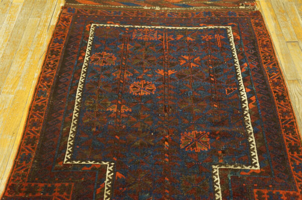 Deep blue and maroon geometric rug featuring medallions and a stepped white inner border on wood flooring.