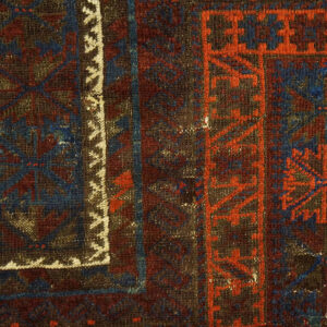 Close-up of a tightly woven, geometric rug pattern in dark blue, maroon, orange, and brown tones.