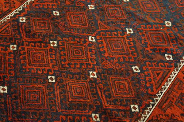 Red and dark blue rug with dense, repeating geometric diamond and square motifs.