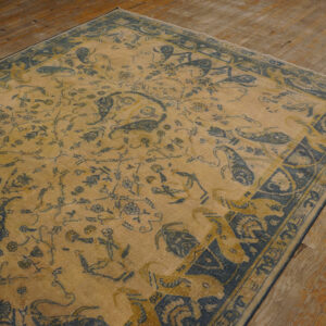 Low-pile gold and indigo traditional rug featuring floral and bōteh patterns on plank wood flooring.