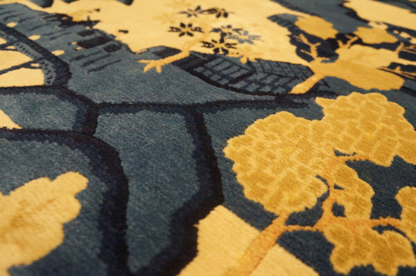 Plush rug detail showing yellow tree designs and carved outlines against a deep blue background.