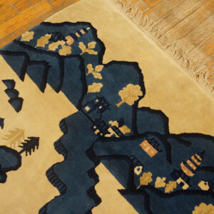 Close-up of a high-pile tan rug featuring a navy landscape design on rustic hardwood flooring.