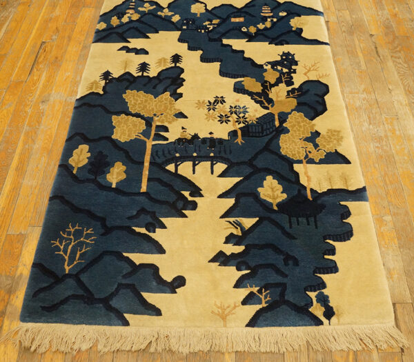 Blue and gold scenic landscape runner rug featuring mountains, trees, and pagodas on a light wood floor.