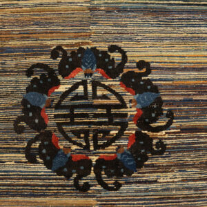 Textured rug detail showing blue, tan, and brown horizontal stripes with a black and red central motif.