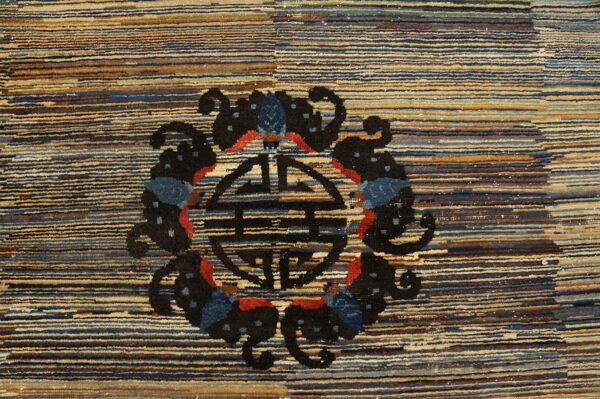 Textured rug detail showing blue, tan, and brown horizontal stripes with a black and red central motif.