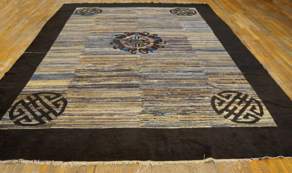Low-pile rug with a dark border and striped blue and tan field, featuring traditional black medallions.