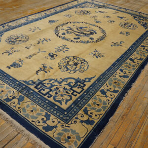 Beige field rug with intricate dark blue border and central dragon medallion on wood flooring.