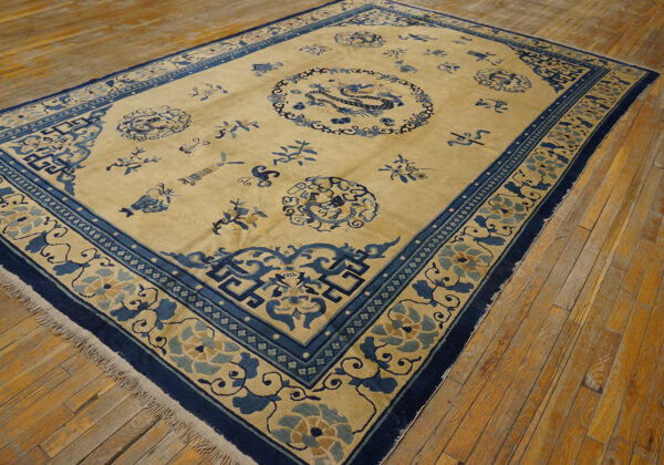 Beige field rug with intricate dark blue border and central dragon medallion on wood flooring.