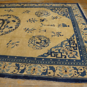 Tan rug with navy blue dragon patterns and complex borders laid on light wood flooring.