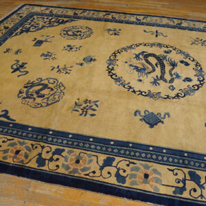 Golden yellow rug with navy blue dragon medallions and scattered traditional motifs on light wood flooring.