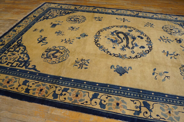 Golden yellow rug with navy blue dragon medallions and scattered traditional motifs on light wood flooring.