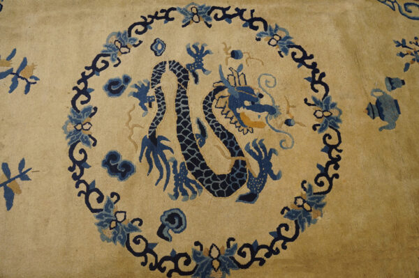 Tan rug field featuring a central dark blue dragon motif surrounded by a detailed blue and navy floral border.