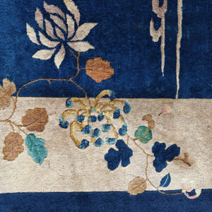 Plush blue and tan rug with floral vines and grape motifs in teal, gold, and pink accents.