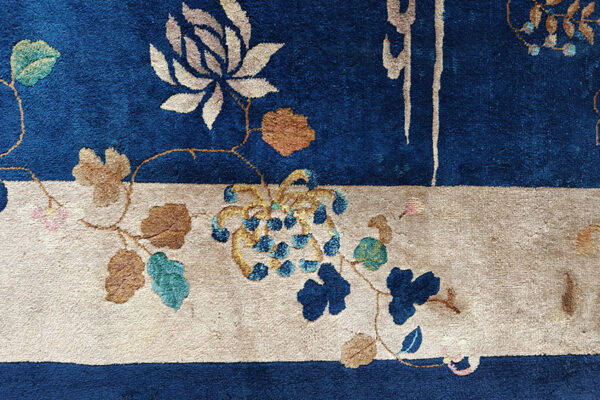 Plush blue and tan rug with floral vines and grape motifs in teal, gold, and pink accents.