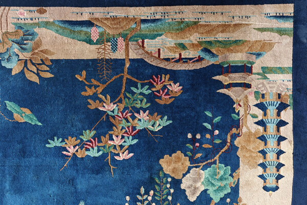 Deep blue rug detail featuring a scenic pattern of flowering vines, tan landscapes, and pagodas.