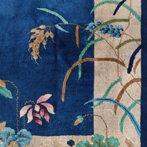 Deep blue plush rug detail featuring an elaborate botanical pattern on a contrasting beige background.