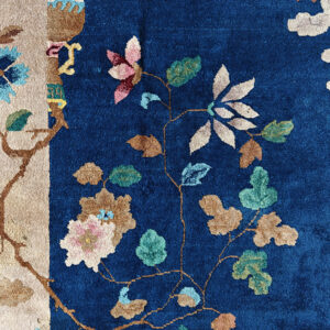 Detailed view of a blue rug showing multicolored floral vines and a contrasting vertical tan border.