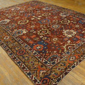 Terracotta rug with complex blue, beige, and orange geometric motifs displayed on wood flooring.