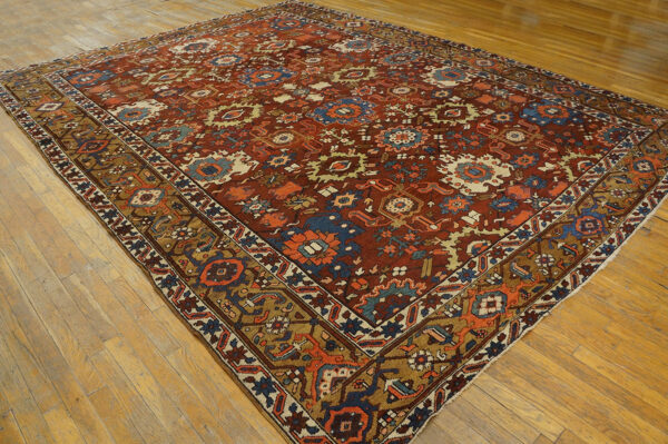 Terracotta rug with complex blue, beige, and orange geometric motifs displayed on wood flooring.