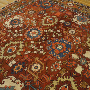 Low pile rug featuring dense geometric patterns in rust, blue, cream, and orange on hardwood flooring.
