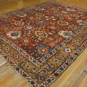 Ornate patterned rug in deep red, blue, and gold tones on distressed wood flooring.