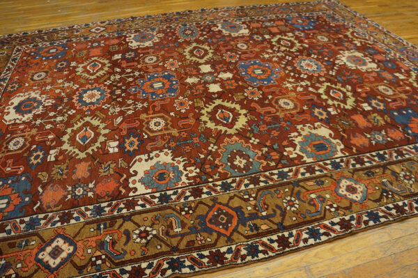 Red-brown rug with complex geometric medallions in blue, cream, and orange, displayed on hardwood flooring.