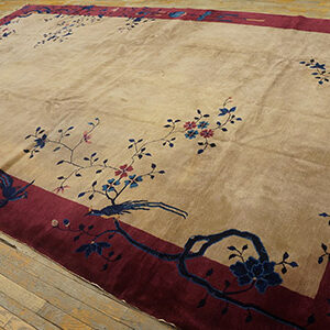 Beige rug with a deep red border, featuring scattered blue and pink floral and bird motifs on wood planks.