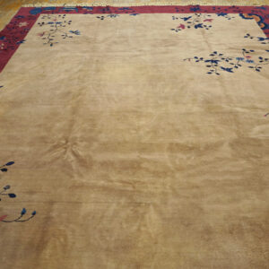 Tan, high-sheen rug featuring a wide burgundy border and blue floral vine patterns on wood planks.